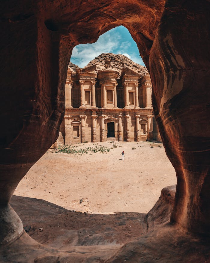 Stunning view of Petra's Monastery framed by a natural cave in Jordan, showcasing ancient architecture.